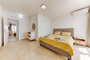 a bedroom with a large bed with a yellow blanket at MonteCasa Seaview Rooms in Dobra Voda