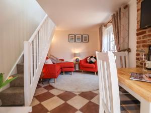 a living room with red chairs and a table at Admiral Cottage in Woodbridge