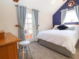 a bedroom with a bed and a desk and a window at Admiral Cottage in Woodbridge