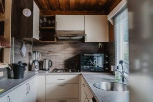 a kitchen with white cabinets and a sink at Cosy and Romantic forest house met SAUNA op de Veluwe in Putten +14 photos