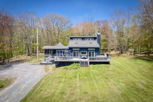 a large blue house with a large yard at The Mountain House Windham Retreat with Hot Tub! in Windham