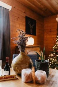 a wooden table with a vase and a christmas tree at Cosy and Romantic forest house met SAUNA op de Veluwe in Putten