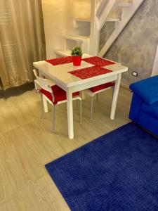 un tavolo bianco con due sedie rosse e un tappeto blu di la Piccola Dimora appartamento a Taranto