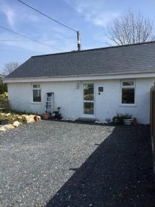 a white house with a gravel driveway in front of it at Orchard Cottage, Pwllheli, North Wales in Pwllheli