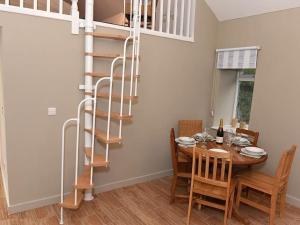 a dining room with a table and a spiral staircase at Orchard Cottage, Pwllheli, North Wales in Pwllheli