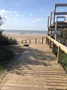un paseo marítimo de madera que conduce a una playa con un banco en SOL Y PLAYA STA en Santa Teresita