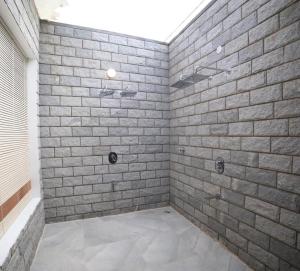 ein Bad mit einer Dusche und einer Ziegelwand in der Unterkunft DWELLINGTON in Kotagiri + 23 Fotos