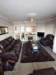 a living room with a leather couch and a fireplace at Ballywalter Beach House in Ballywalter