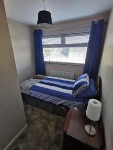 1 dormitorio con 1 cama con cortinas azules y ventana en Ballywalter Beach House, en Ballywalter