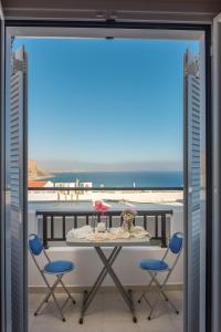 einen Tisch und Stühle auf einem Balkon mit Meerblick in der Unterkunft Antigoni in Agia Galini