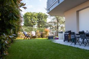 een achtertuin met stoelen, een grill en gras bij Estate in Desenzano del Garda