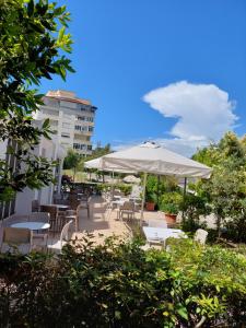 eine Terrasse mit Tischen, Stühlen und einem Sonnenschirm in der Unterkunft Hotel Nacional Durres in Durrës