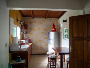 cocina con nevera, mesa y sillas en La petite Maison Bakov’ en Montjoly