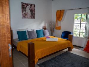 1 dormitorio con 1 cama con manta naranja y almohadas azules en La petite Maison Bakov’, en Montjoly
