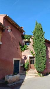 um edifício de tijolos vermelhos com uma árvore ao lado em Maison Porte Heureuse em Roussillon