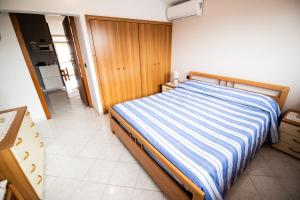 - une chambre dotée d'un lit avec des draps rayés bleus et blancs dans l'établissement Stella Marina siderno, à Siderno Marina