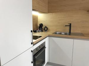 a kitchen with white cabinets and a sink at Аpartment Bella Vista in Obzor