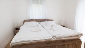 uma cama com lençóis brancos e almofadas em River&Lake Luxury I. Apartman em Sárvár