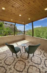 patio con sillas, mesa y techo de madera en Fragrant Rose, en Wadi Musa