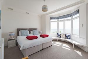a white bedroom with a large bed with red pillows at Seagulls by Bloom Stays in Folkestone