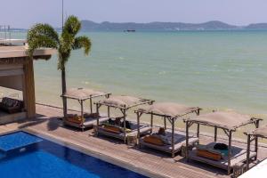 a row of beds next to a swimming pool next to the water at Selina Serenity Rawai Phuket in Rawai Beach