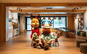 two moose characters sitting on chairs in a room at Hotel Alpestre in Gramado