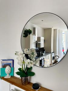 a mirror reflecting a kitchen with a vase of flowers on a shelf at One Abbey Court in Whitby