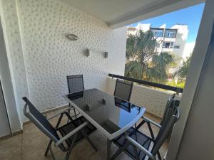 una mesa y sillas en una habitación con balcón en Appartement Assilah marina golf, en Asilah