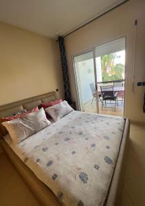 een slaapkamer met een bed en uitzicht op een patio bij Appartement Assilah marina golf in Asilah