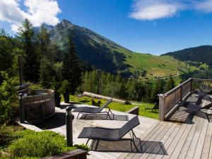 a deck with a table and chairs and a mountain at Chalet La Clusaz, 6 pièces, 12 personnes - FR-1-437-57 in La Clusaz