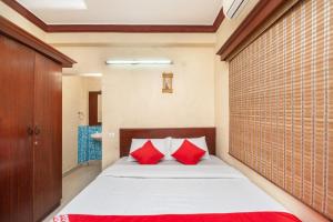 um quarto com uma cama com duas almofadas vermelhas em OYO Sr Pradeep Park em Chennai