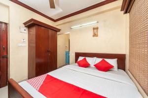 um quarto com uma cama grande e almofadas vermelhas em OYO Sr Pradeep Park em Chennai