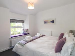 a bedroom with a large white bed with purple pillows at Greenstyles in Bowness-on-Windermere