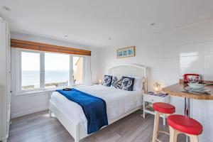 a white bedroom with a bed and a table and chairs at Pebbles by Bloom Stays in Sandgate