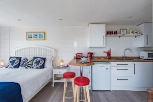a bedroom with a bed and a kitchen with red stools at Pebbles by Bloom Stays in Sandgate