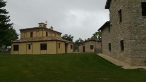 un edificio con un patio de césped junto a un edificio en BorgoPratole CountryHouse, en Cingoli