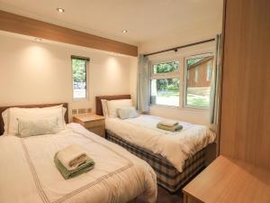 a small bedroom with two beds and a window at Forest Pines Lodge in Bowness-on-Windermere