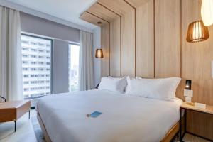 a large white bed in a hotel room with a window at Radisson Pinheiros in Sao Paulo