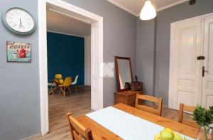 a dining room with a table and a clock on the wall at Blue Dollar Apartament in Przemyśl