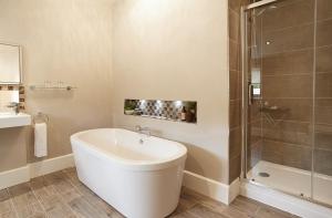 W łazience znajduje się biała wanna i prysznic. w obiekcie The Gardener's Bothy Shropshire w mieście Weston under Lizard