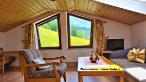 ein Wohnzimmer mit einem Sofa, einem Tisch und 2 Fenstern in der Unterkunft Ferienhaus hoch oben mit Alpen Panorama Königssee- Nichtraucherdomizil in Berchtesgaden