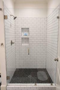a bathroom with a shower with white tiles at Modern Midtown home with 3 king beds in Memphis