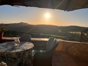 a table and chairs on a balcony with the sunset at Costa Smeralda appartamento Pevero Golf in Arzachena