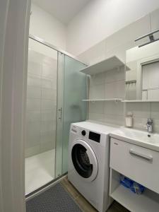 a white bathroom with a washing machine and a sink at Noelle apartment in Ljubljana