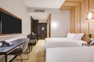 a hotel room with two beds and a desk and a tv at Radisson Pinheiros in São Paulo