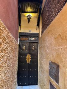 Una puerta negra en un edificio con un cartel. en DAR ALKATIB MEKNES, en Meknès