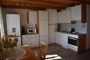 una pequeña cocina con armarios blancos y una mesa con mesa en Ferienwohnung en Fraxern