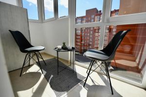 2 Stühle und ein Tisch vor einem Fenster in der Unterkunft Cozy apartment next to the park in Ternopil