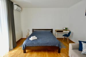 a bedroom with a blue bed and a couch at Cozy apartment next to the park in Ternopilʼ