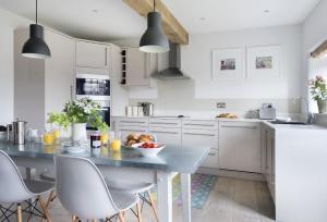 a kitchen with white cabinets and a table and chairs at Mole End Cottage in North Cerney